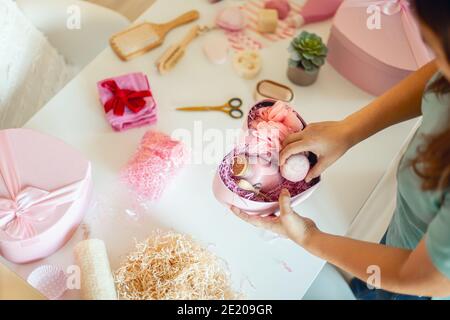 Frau Vorbereitung rosa gefärbte herzförmige Geschenk-Boxen mit Bio Naturkosmetik der Körperpflege Stockfoto