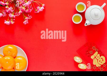 Chinesisches Neujahr rot Hintergrund mit Tee-Set, roten Umschlag-Päckchen oder ang bao (Wort bedeutet Reichtum), Goldbarren, Orangen und chinesischen Blüten. Stockfoto