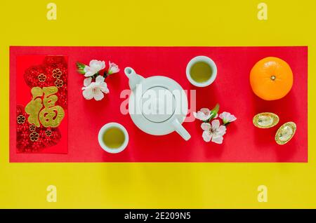 Chinesisches Neujahr gelb und rot Hintergrund mit Tee-Set, chinesische Blüten, Goldbarren, Orangen und roten Umschlag-Paket oder ang bao (Wort bedeutet Stockfoto