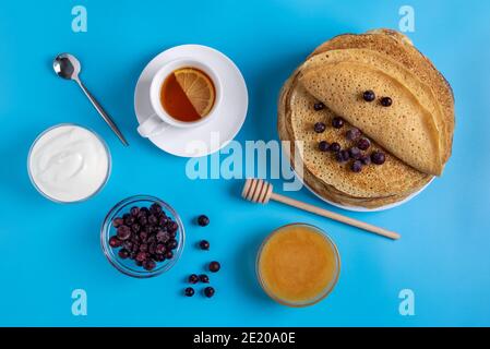 Nahaufnahme der russischen nationalen Küche und Dessert-Pfannkuchen mit saurer Sahne, Beeren und Honig. Traditionelles Gericht für Fasching. Selektiver Fokus Stockfoto