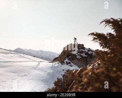 Mann mit Rucksack zu Fuß auf dem Felsen in der schönen Berge bei Sonnenuntergang Hintergrund Stockfoto