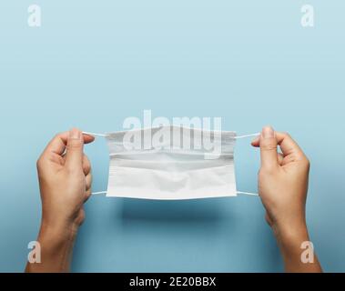 Ein Mann hält Gesichtsmaske über blauem Hintergrund. Stockfoto