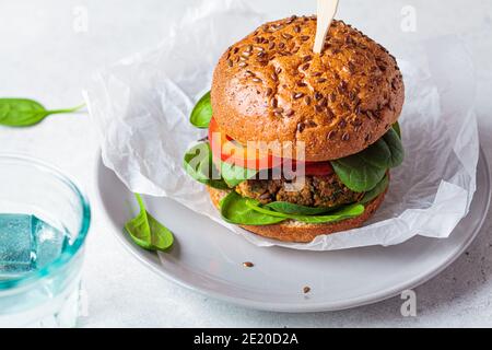 Veganer Linsenburger mit gebackener Süßkartoffel, Tomatensauce und frischem Gemüse auf einem grauen Teller. Veganes Lebensmittelkonzept. Stockfoto