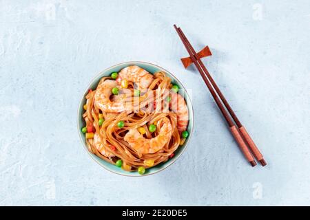 Würzige Nudeln mit Garnelen und Gemüse, Overhead-Schuss mit Essstäbchen Stockfoto