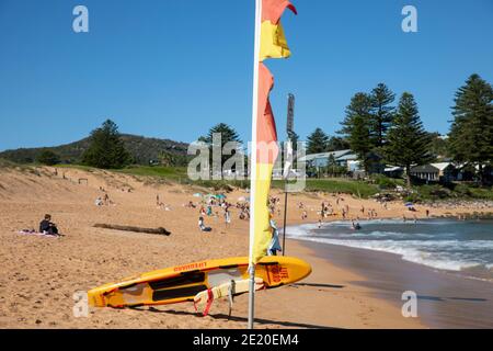 Sydney Surf Rettung Surfbrett und roten und gelben Fahnen zu Sichere Badegebiete am Avalon Beach in Sydney, Australien Stockfoto