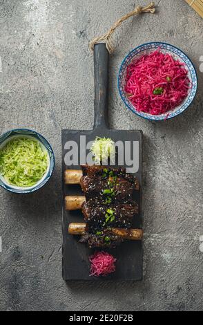 Rinderrippen, koreanischer Stil auf schwarzem Holzbrett, Draufsicht. Stockfoto