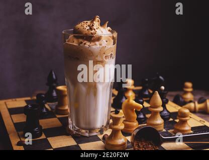 Dalgona Kaffee. Schlagsahngetränk mit Instant-Kaffee beliebt in Korea cremigen Cocktail in hohen Gläsern mit Schach auf Holzchessboard dekoriert Stockfoto