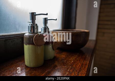 Keramikflaschen mit Shampoo und Duschgel werden in eine große Holzschale gestellt. Und setzen Sie auf die hölzerne Theke Frosted Glas Hintergrund Konzept Thai Spa f Stockfoto