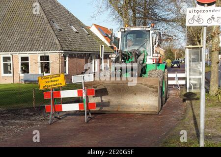 Rad Bulldozer mit Eimer an der Straße in der niederländischen Dorf Bergen während des Baus der Straße. Verkehrszeichen Stockfoto