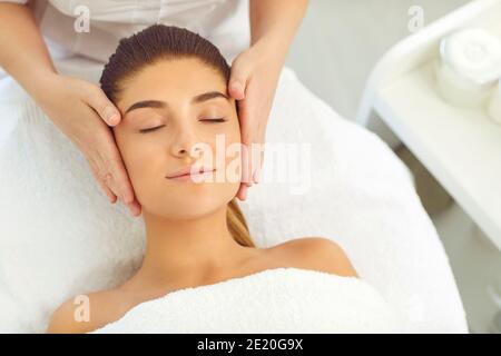 Gesichtsmassage. Die Hände des Kosmetikers massieren entspannte Frauen Gesicht im Spa Schönheitssalon Stockfoto