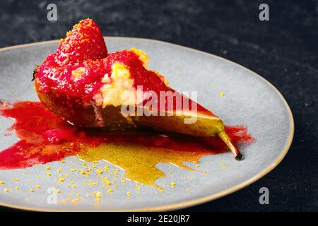 Nahaufnahme von süß gebackenen Birnen mit Mascarpone, Karamellsirup und Erdbeermarmelade Stockfoto
