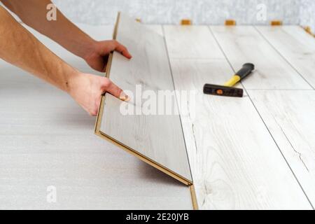 Männliche Hände legt Holzplatte Laminatboden drinnen Nahaufnahme. Stockfoto