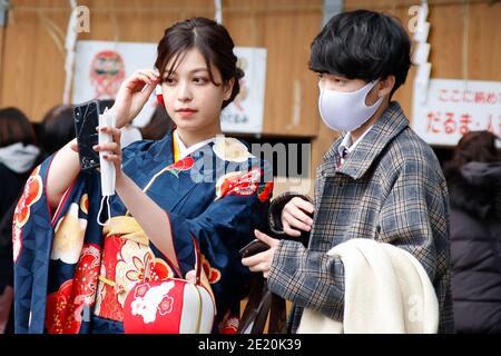Tokio, Japan. Januar 2021. Ein japanisches Mädchen in bunten Kimono posiert für ein Selfie mit ihrer Freundin am Eingang des Meiji Shrine während des Coming of Age Day. Der Coming of Age Day (Seijin-no-Hi) ist ein Feiertag, um all jenen zu gratulieren und sie zu ermutigen, die in Japan Erwachsene geworden sind (20 Jahre alt). Die jährliche Feier findet am zweiten Montag im Januar statt, obwohl viele der normalerweise jubelnde Ereignisse wegen der Ängste vor dem Coronavirus abgesagt wurden. Quelle: Rodrigo Reyes Marin/ZUMA Wire/Alamy Live News Stockfoto