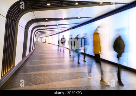 Abstrakte Bewegungsunschärfe von Menschen, die durch unterirdische Lichttunnel gehen Stockfoto