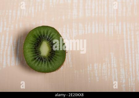 Kiwi Obst in zwei Hälften geschnitten. Saftiges grünes Fruchtfleisch ist sichtbar. Auf einer beigen Oberfläche. Stockfoto