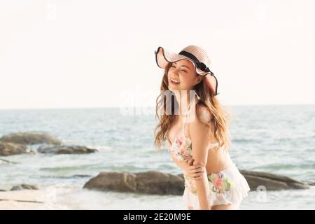 Portrait von lächelnd schöne junge Frau trägt Sommerhut mit großer Krempe am Strand. Stockfoto