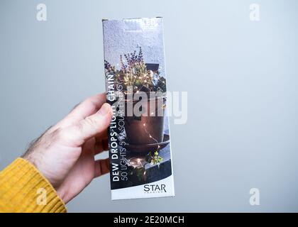 Paris, Frankreich - Dec 13, 2020: POV männliche Hand hält Dew Drops Licht Kette von LED-Leuchten mit Solarenergie angetrieben Stockfoto