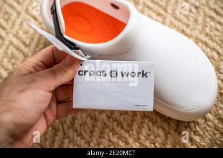 Paris, Frankreich - Dez 13, 2020: POV männliche Hand hält Papier Werbeschild von Crocs bei der Arbeit bequeme Schuhe mit Preisschild Etikette Stockfoto