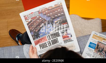 Paris, Frankreich - 7. Januar 2020: Frau liest auf Couch die französische Zeitung Liberation auf der Titelseite zeigt am 07. Januar 2021 den Sturm auf das US-Kapitol durch Anhänger des US-Präsidenten Donald Trump Stockfoto