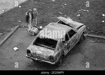 Kleine Kinder neben einem verbrannten Auto, September 1986, Ballymun, Dublin, Republik Irland Stockfoto