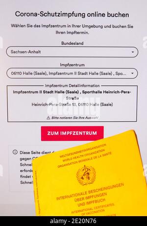 Leipzig, Deutschland. Januar 2021. Eine Hand hält eine Impfkarte vor einem Bildschirm mit der Terminvergabeseite für Corona-Impfungen. In Sachsen und Sachsen-Anhalt starten die Impfzentren am selben Tag in Betrieb. Während in Sachsen 13 Zentren beginnen, gibt es 14 in Sachsen-Anhalt. Quelle: Jan Woitas/dpa-Zentralbild/dpa/Alamy Live News Stockfoto