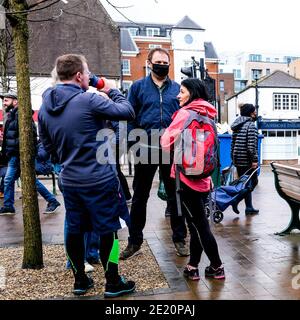 London Großbritannien, kleine Gruppe von Menschen einige tragen Schutzgesichtenmasken Trinken Takeaway Kaffee stehend Reden an EINEM Wet Winters Day während Covid-19 Loc Stockfoto