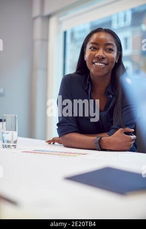 Lächelnde Afroamerikanische Geschäftsfrau, Die Am Tisch Im Büromeeting Sitzt Zimmer Stockfoto