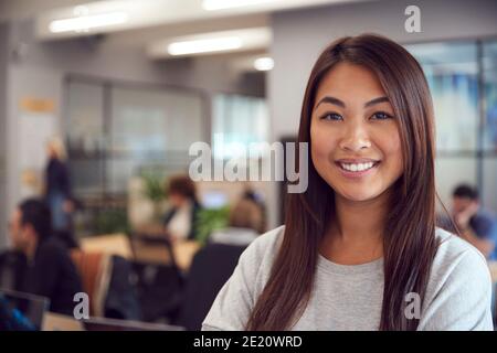 Kopf Und Schultern Porträt Von Lächelnd Junge Asiatische Geschäftsfrau Arbeiten In Einem Geschäftigen Modernen Büro Stockfoto