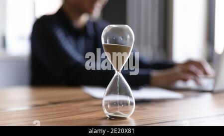 Nahaufnahme der Sanduhr, die die Zeit auf dem Holztisch misst Stockfoto