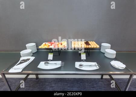 Viele süße Muffins und Obst in Scheiben auf einem servierten Tisch in einer Kaffeepause im Büro. Stockfoto