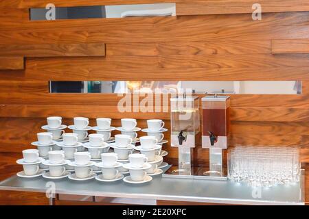 Viele leere weiße Tee- oder Kaffeetassen, Gläser und große Saftflaschen auf dem Tisch. Catering-Service Für Veranstaltungen. Stockfoto