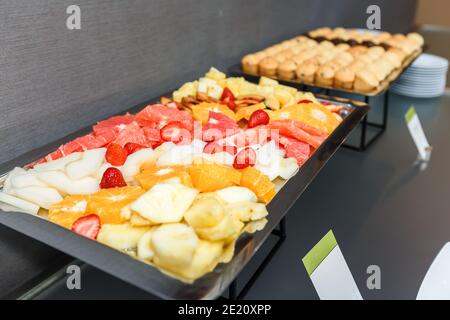 Obst in Scheiben und süße Muffins auf einem servierten Tisch in einer Kaffeepause im Büro. Stockfoto