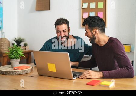 Gay Männer paar mit Laptop im Wohnzimmer zu Hause - homosexuelle Liebe und Geschlechtergleichstellung in Beziehungskonzept Stockfoto