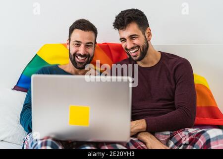 Glücklich Gay Männer paar mit Laptop im Bett - homosexuell Liebe und Gleichstellung der Geschlechter im Beziehungskonzept Stockfoto