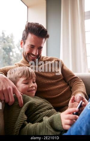 Vater Und Sohn Auf Sofa Zu Hause Mit Spaß Spielen Spiel Auf Dem Handy Stockfoto