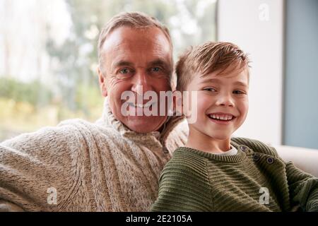 Portrait Des Enkels Sitzt Auf Sofa Zu Hause Mit Großvater Stockfoto