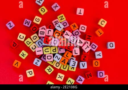 Bunte Holzwürfelperlen mit Buchstaben auf rotem festlichem Hintergrund, Wort "Liebe". Valentinstag. 14 Februar. Flach liegend, Draufsicht. Stockfoto