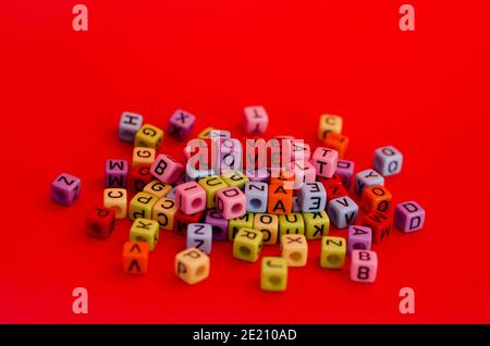 Bunte Holzwürfelperlen mit Buchstaben auf rotem festlichem Hintergrund, Wort "Liebe". Valentinstag. 14 Februar. Flach liegend, Draufsicht. Stockfoto