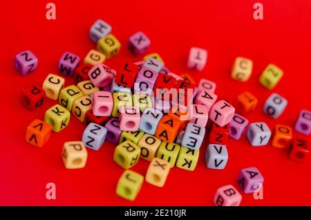 Bunte Holzwürfelperlen mit Buchstaben auf rotem festlichem Hintergrund, Wort "Liebe". Valentinstag. 14 Februar. Flach liegend, Draufsicht. Stockfoto