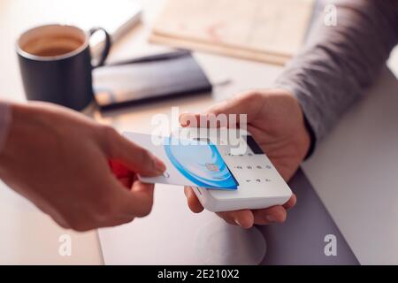 Frau, Die Kontaktlose Zahlung Mit Kreditkarte An Man Holding Macht Kartenleser Stockfoto