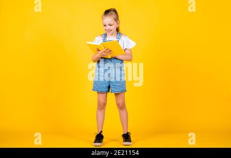 Nettes Kind geht, um Informationen aus dem Buch zu lesen, zurück zur Schule. Stockfoto