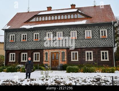 Buckow, Deutschland. Januar 2021. Thomas Mix (SPD), Bürgermeister von Buckow, steht vor seinem Umbindehaus. Thomas Mix zog nach Buckow und brachte sein ganz besonderes Haus mit. Seitdem ist es in der Märkischen Schweiz eine Seltenheit geworden: Denn umgebinde Häuser sind vor allem in der Oberlausitz typisch. Mix ist jetzt Bürgermeister in Buckow und sein Haus ist ein Blickfang. Quelle: Patrick Pleul/dpa-Zentralbild/ZB/dpa/Alamy Live News Stockfoto