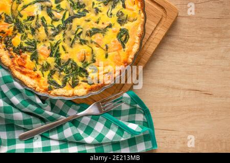 Blick von oben auf Meeresfrüchte und Lachs Fisch Quiche Pie mit Baby Spinat Blätter- hausgemachte Rezept Pie auf Holztisch Hintergrund mit Kopierer Platz serviert Stockfoto