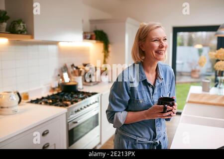 Lachende Reife Frau Zu Hause In Der Küche Kaffee Trinken Stockfoto