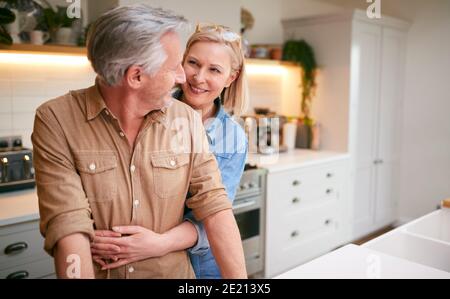 Loving Reifen Paar Umarmt, Wie Sie Stehen Von Zähler In Küche Zu Hause Stockfoto