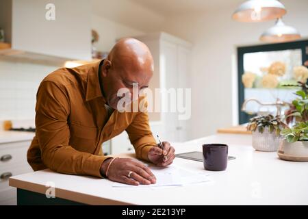 Reifer Mann Überprüfung Und Unterzeichnung Inländischen Finanzen Und Investitionen Papierkram In Der Küche Zu Hause Stockfoto