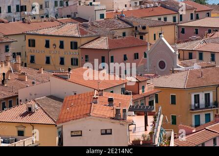 Portoferraio Dorf mit der Spitze der Geburt der Jungfrau Maria Kirche, die sich unter den Häusern, Elba Island, Toskana, Italien Stockfoto