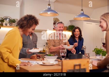 Gruppe Von Reifen Freunden Treffen Zu Hause Serving Essen Bei Dinner Party Und Wein Trinken Zusammen Stockfoto