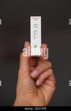 Hand halten und einen negativen Coronavirus-Blut-Antikörper-Test zeigen Auf einem dunklen, schlichten Hintergrund Stockfoto