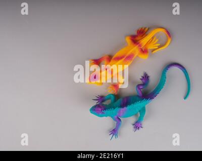 Spielzeug-Leguan-Eidechse auf grauem Hintergrund, Konzeptfoto, Platz für Text. Stockfoto